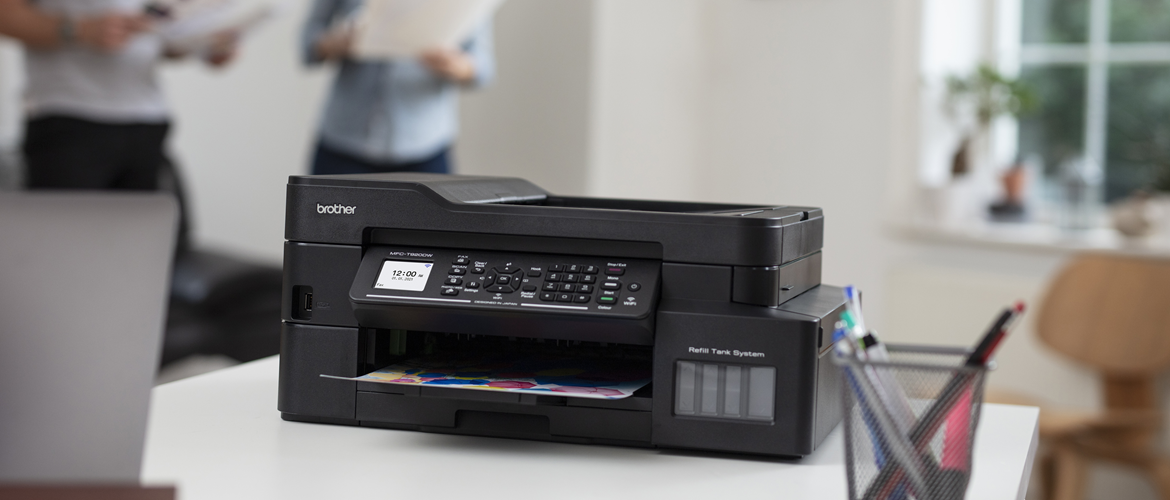 A black Brother MFC printer with a double-sided colour printed output and a hand seen picking the paper up