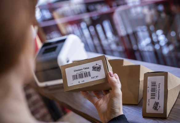 Жена член проверява отпечатаните етикети за хранителни продукти, отпечатани на етикетен принтер Brother